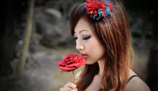 Mujer japonesa sosteniendo una rosa roja